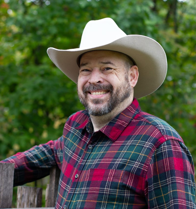 Daniel J. Wagner, founder of MyAdAssist, smiling outdoors in a cowboy hat and plaid shirt